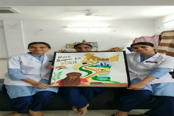 नर्सिंग वर्दी में तीन छात्राएं ‘मेरे सपनों का भारत’ लिखा चित्र हाथ में लेकर बैठी हैं
